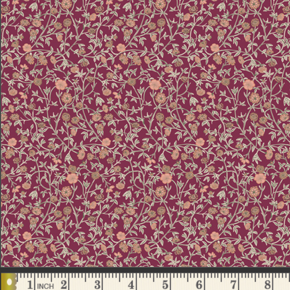 A close-up of a floral fabric pattern with small peach and beige flowers on a deep burgundy background, with a ruler along the bottom edge showing measurement scale.