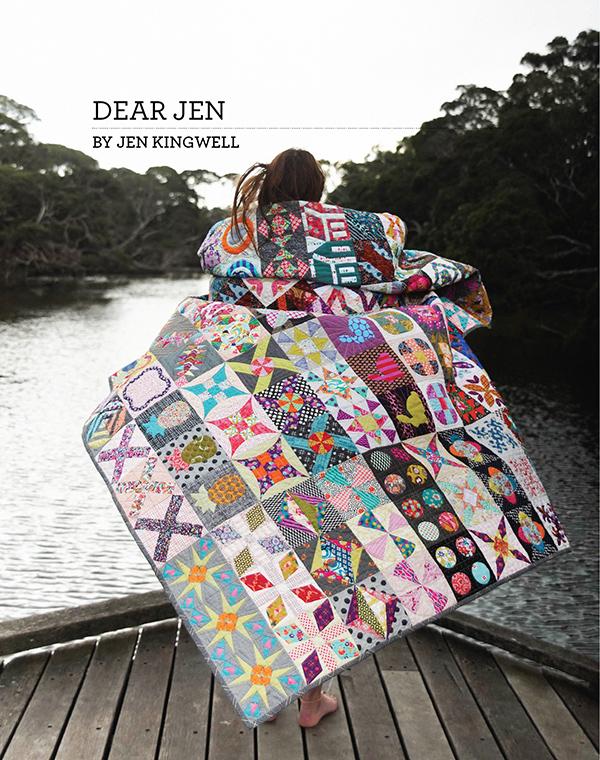 The image shows a woman standing on a dock at a river with a bright, vibrant quilt wrapped around her, flowing in the wind. Text at the top left says “Dear Jen by Jen Kingwell.”