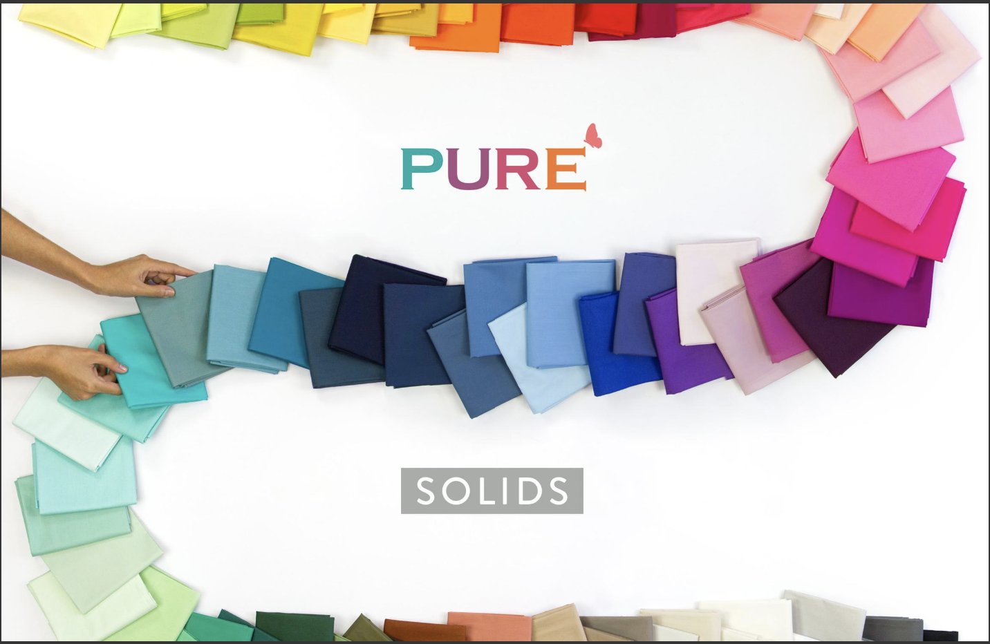 The image shows dozens of fabric cuts in solid colors arranged in rainbow order and in a curving line, much like a domino run.