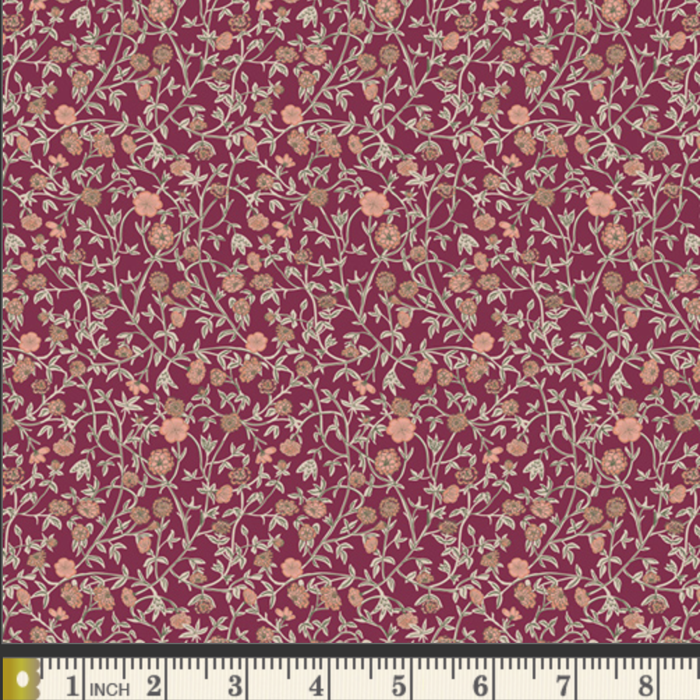 A close-up of a floral fabric pattern with small peach and beige flowers on a deep burgundy background, with a ruler along the bottom edge showing measurement scale.