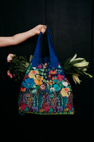 Colorful floral-patterned bag held by a hand against a black background